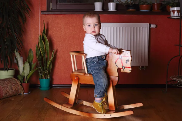 Cute boy riding wooden horse — Stock Photo, Image