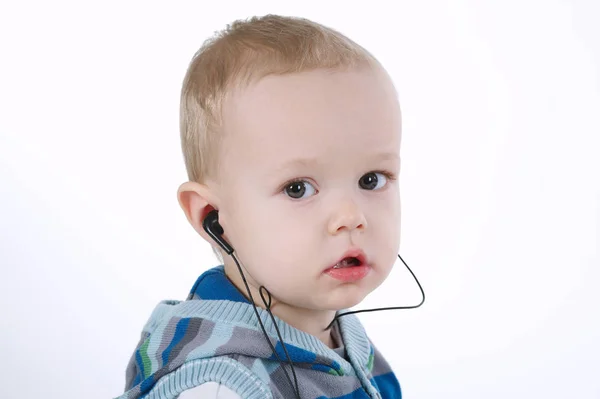 Menino bonito ouve música com fones de ouvido — Fotografia de Stock