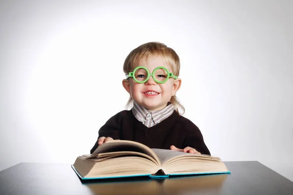 Ragazzo in occhiali divertenti libro di lettura su bianco — Foto Stock
