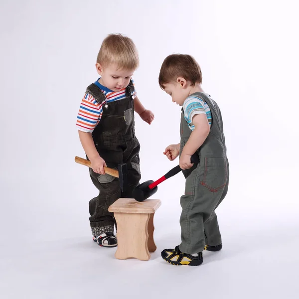 Dois meninos pequenos que reparam a cadeira no branco — Fotografia de Stock