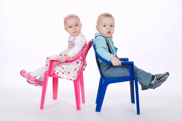 Legrační chlapec a dívka sedí na židlích, zády k sobě — Stock fotografie