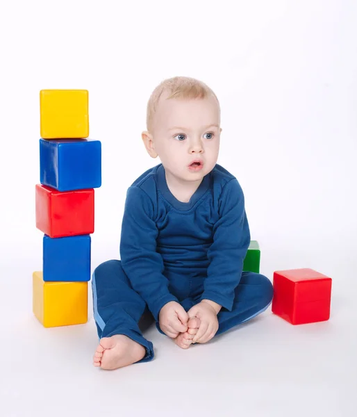 Ragazzo gioca con cubi su bianco — Foto Stock