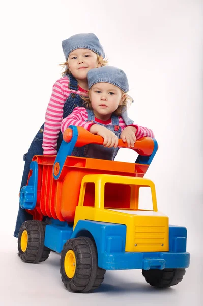 Two funny twins girls with toy car — Stock Photo, Image