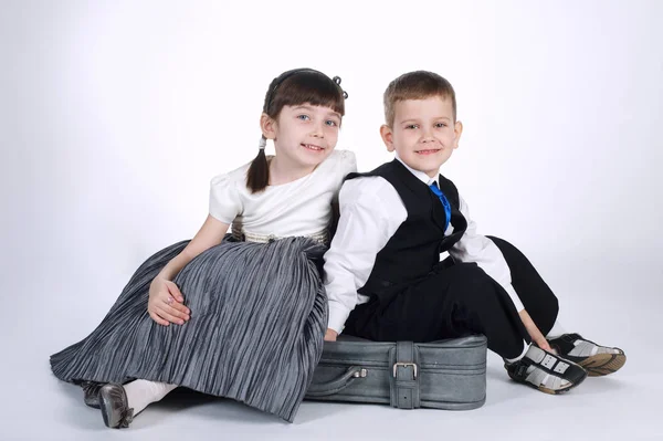 Heureux garçon et fille assis sur valise — Photo
