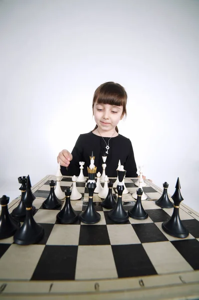 Маленькая девочка играет в шахматы на белом — стоковое фото