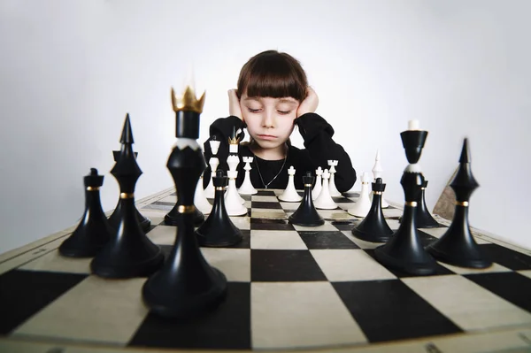 Маленькая девочка играет в шахматы на белом — стоковое фото