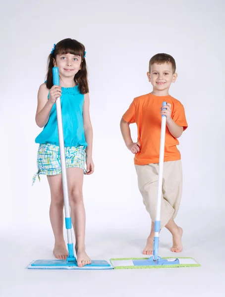Kleines Mädchen und Junge mit Wischmopp auf weiß — Stockfoto
