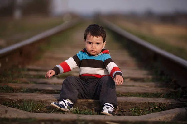 Pequeno menino bonito joga no caminho de ferro — Fotografia de Stock