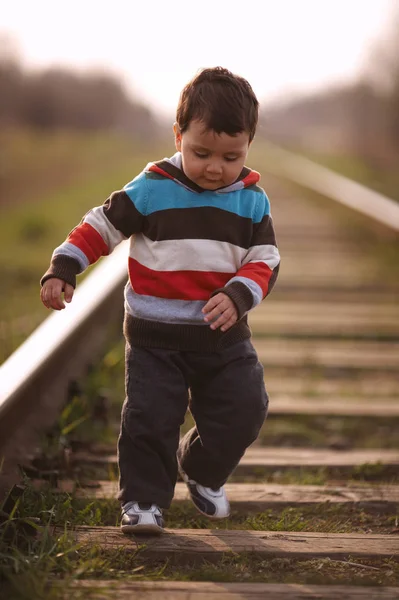 Pequeno menino bonito joga no caminho de ferro — Fotografia de Stock