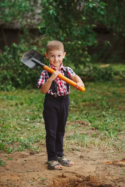 Vicces kisfiú lapáttal kertben — Stock Fotó
