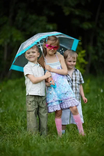 Happy children under umbrella in park — Stock Photo, Image