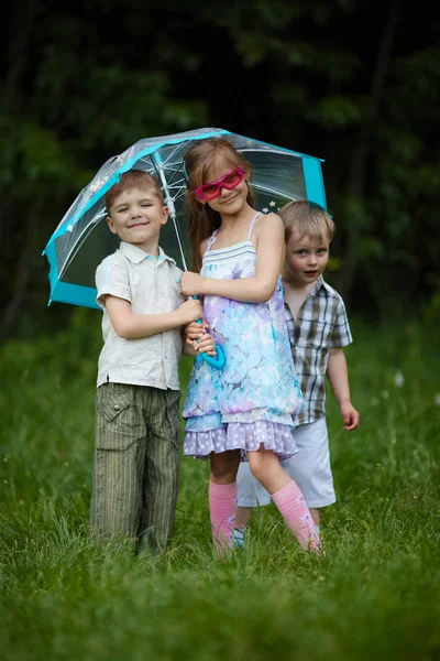 Crianças felizes sob guarda-chuva no parque — Fotografia de Stock