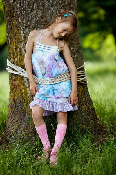 Girl tied to tree in park — Stock Photo, Image