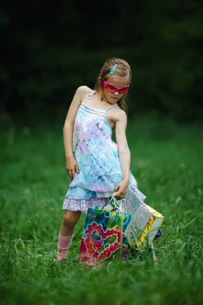 Girl with shopping bags in summer park — Stock Photo, Image