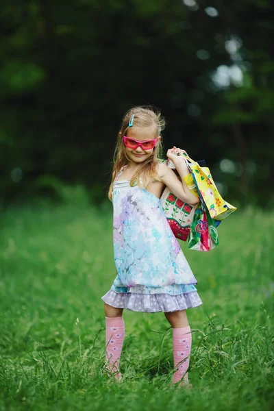 Girl with shopping bags in summer park — Stock Photo, Image