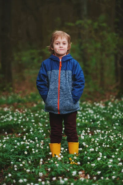 Niño pequeño en el bosque de primavera con muchas flores — Foto de Stock