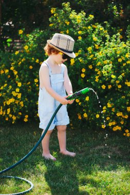 küçük çocuk bahçe hortumu ile sulama