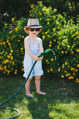 küçük çocuk bahçe hortumu ile sulama