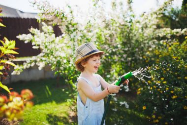 küçük çocuk bahçe hortumu ile sulama