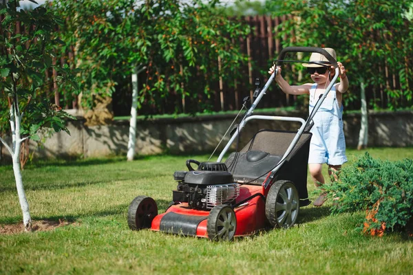 Мальчик стрижет газон косилкой — стоковое фото