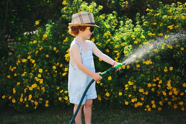 Menino molhando o jardim com mangueira — Fotografia de Stock