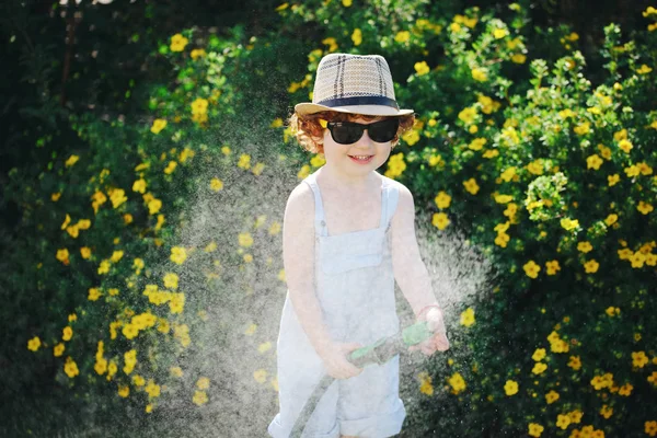 Niño regando el jardín con manguera — Foto de Stock