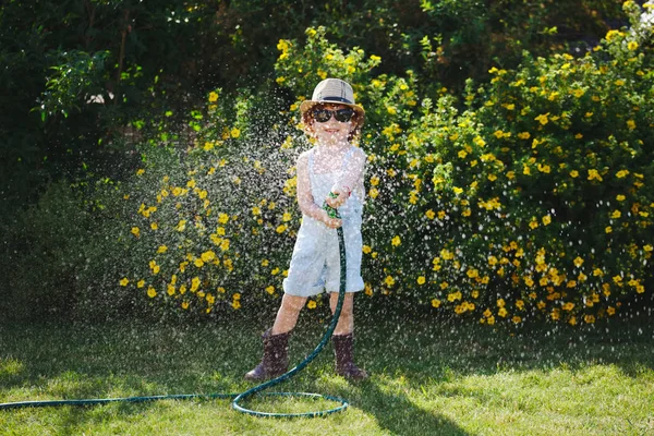 Niño regando el jardín con manguera — Foto de Stock