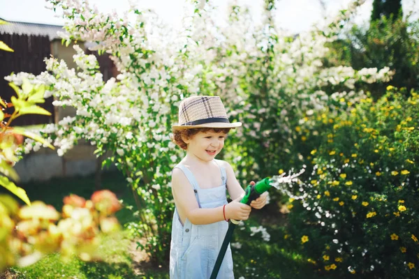 Bambino che innaffia il giardino con il tubo — Foto Stock