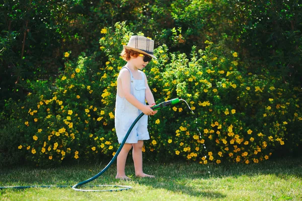 Niño regando el jardín con manguera — Foto de Stock