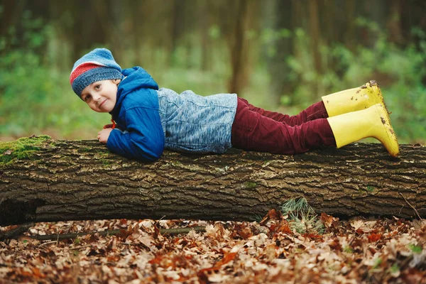 Piccolo divertente ragazzo su grande log — Foto Stock