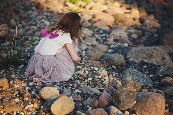 Kleines Mädchen spielt auf Steinen am Strand — Stockfoto