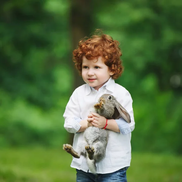 Jongetje met konijn op gras — Stockfoto