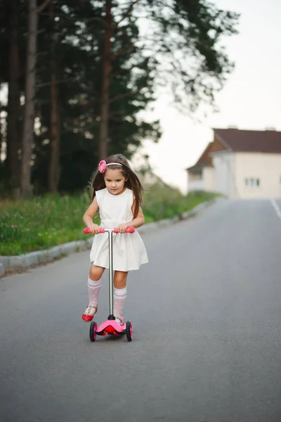 Krásná dívka s koloběžkou na silnici — Stock fotografie