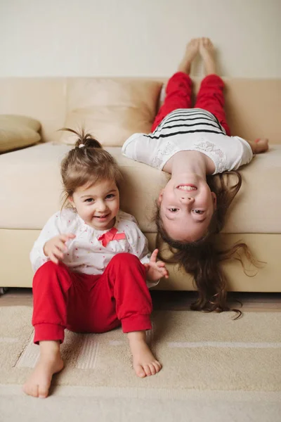Małe słodkie dziewczyny na kanapie do góry nogami w dół — Zdjęcie stockowe