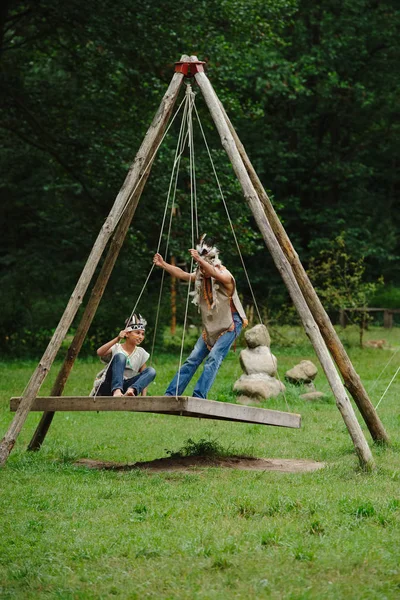 Boys playing native american on swings — Stock Photo, Image