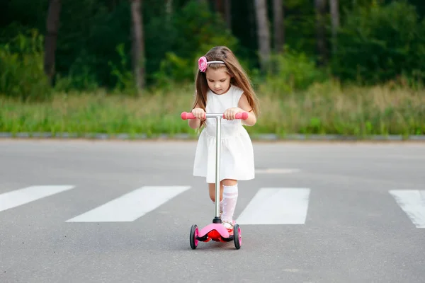 Красивая девушка со скутером на дороге — стоковое фото