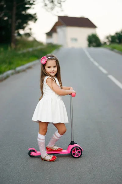 Beautiful girl with scooter on the road — Stock Photo, Image