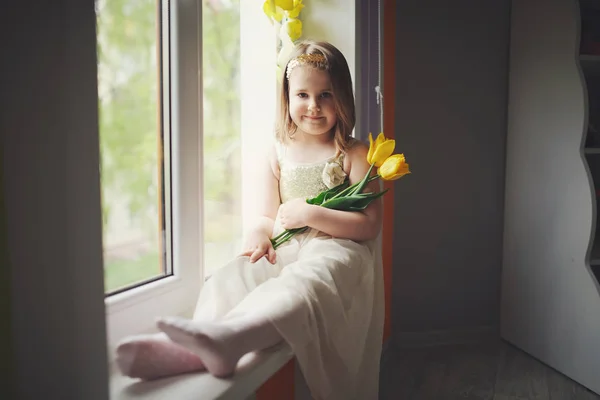 Lustiges Mädchen mit gelben Tulpen zu Hause — Stockfoto