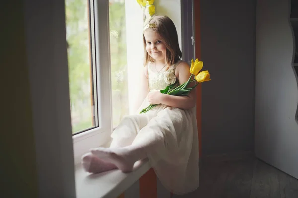 Lustiges Mädchen mit gelben Tulpen zu Hause — Stockfoto