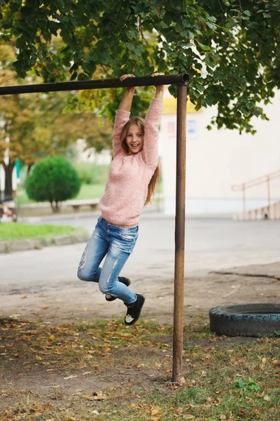 Young happy girl swinging on the crossbar — Stock Photo, Image