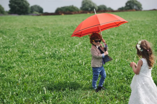 Мальчик и девочка под красным зонтиком — стоковое фото