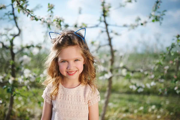 Beautiful little girl in blooming garden — Stock Photo, Image