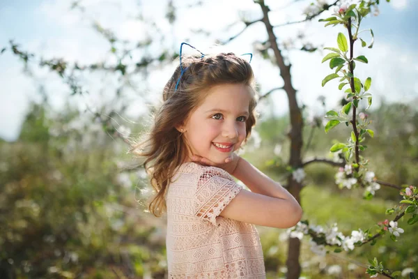 Beautiful little girl in blooming garden — Stock Photo, Image