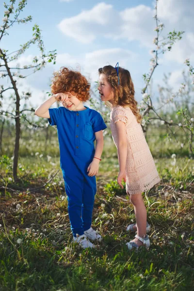 Liten pojke och flicka i blommande trädgård — Stockfoto