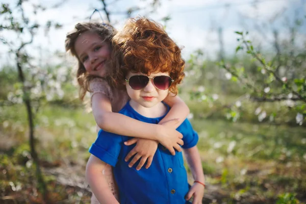 Liten pojke och flicka i blommande trädgård — Stockfoto