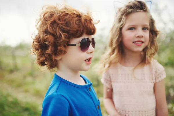 Kleine jongen en meisje in de bloeiende tuin — Stockfoto