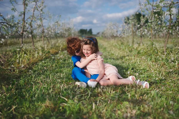 Liten pojke och flicka i blommande trädgård — Stockfoto