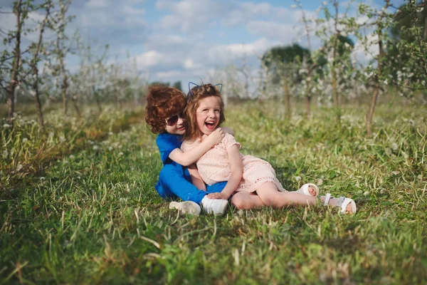 Liten pojke och flicka i blommande trädgård — Stockfoto