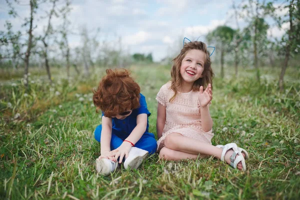 Küçük erkek ve kız çiçek açan bahçesinde — Stok fotoğraf