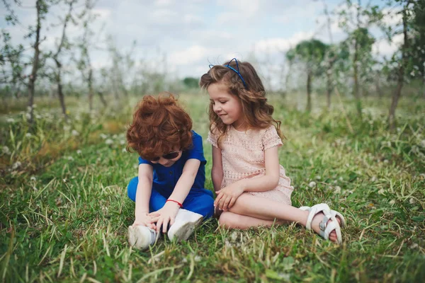 Kleine jongen en meisje in de bloeiende tuin — Stockfoto